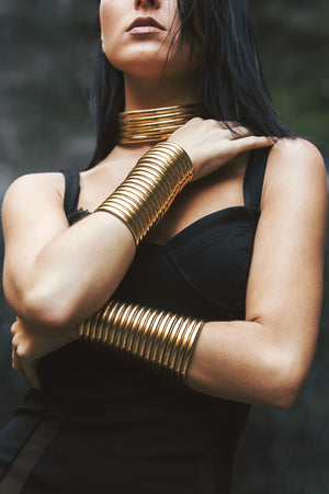 Close up of woman posing with two Gold Gladiator Cuffs and a Gold Ndebele Choker