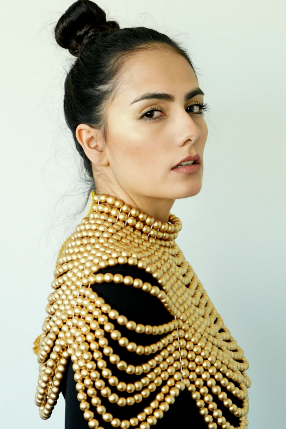 Close up of woman in a black long-sleeve dress posing with the Gold Cleopatra necklace