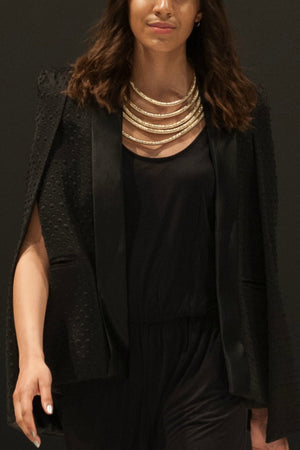 Woman walking a runway wearing the Black Cape, a Black jumpsuit and a Gold Rope Necklace